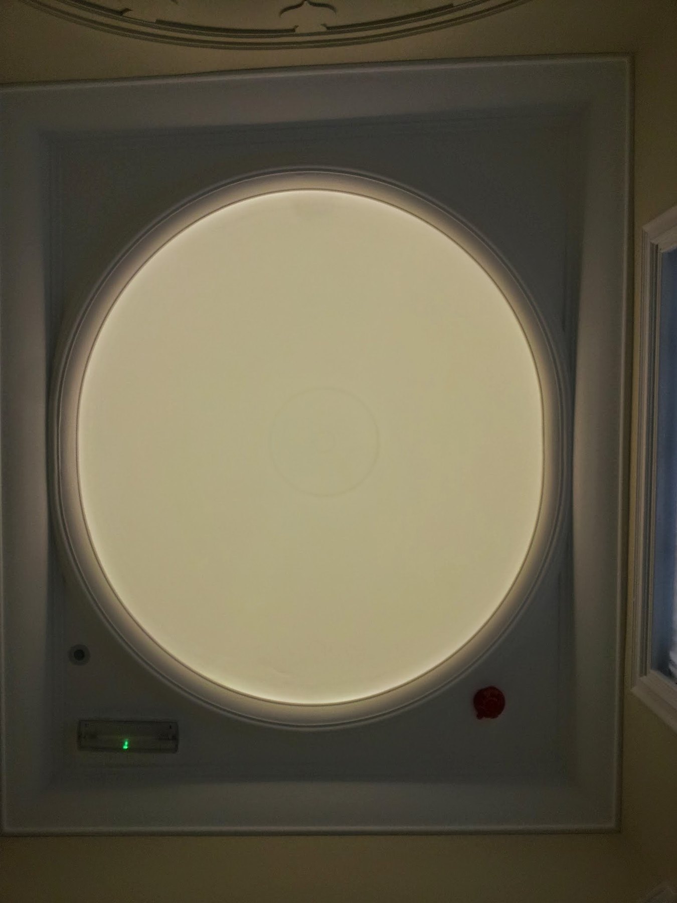 A round, lit ceiling dome seen from directly below, set in a moulded frame