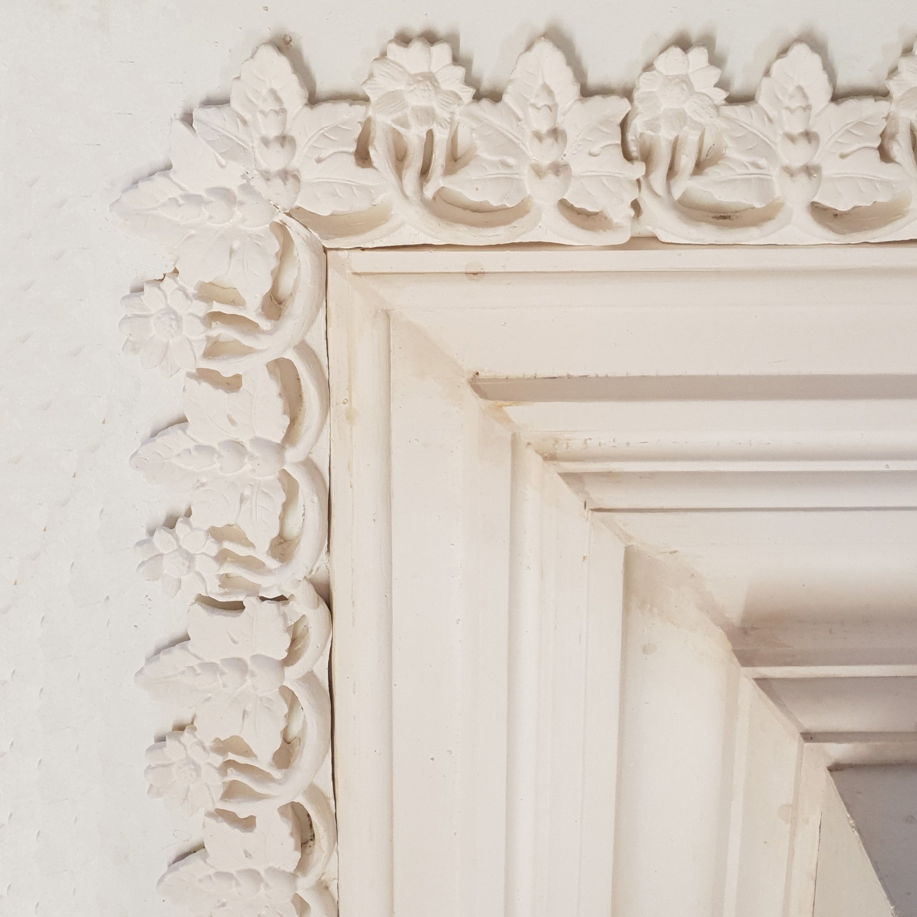 A corner of cornice with a leaf and flower enrichment running round it