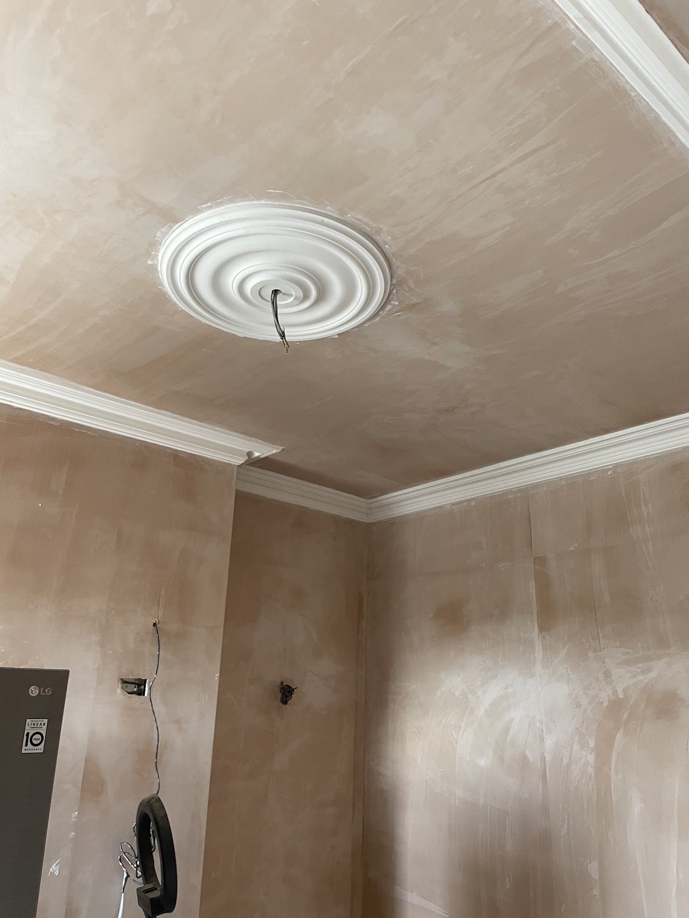 A plain ceiling rose and new cornice in a freshly plastered room